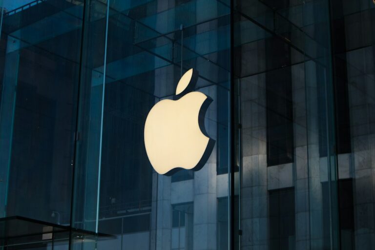 ガラス張りの建物に掲げられた、明るく光るAppleのロゴ